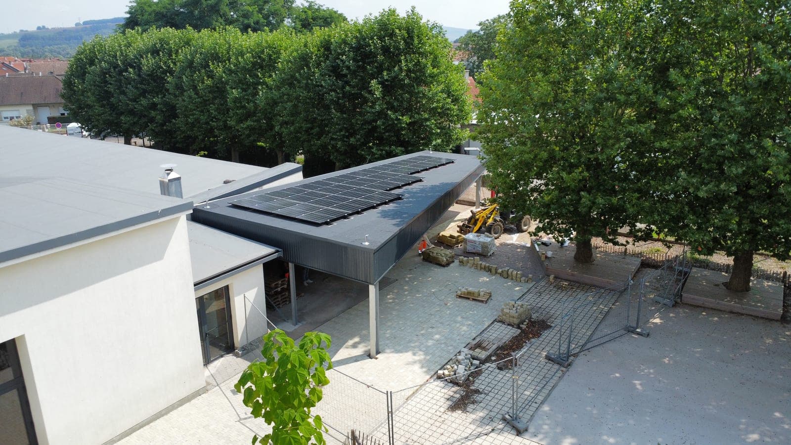 Préau d'école photovoltaïque en charpente métallique adossé au bâtiment scolaire, à Dieulouard (54)