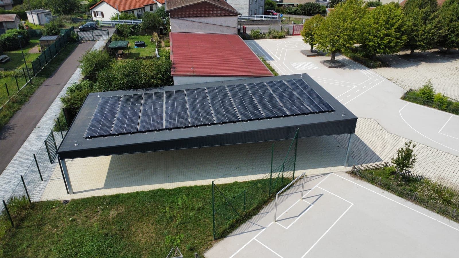 Toiture du préau entièrement couverte de panneaux photovoltaïques, cour de l'école de Dieulouard (54)